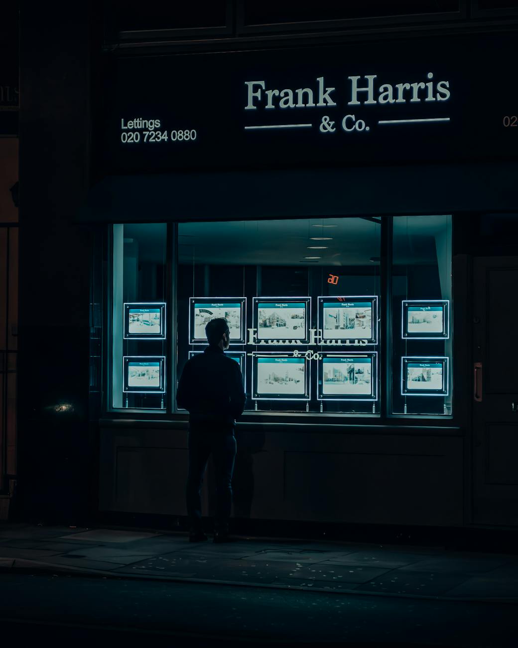 man standing by store window at night